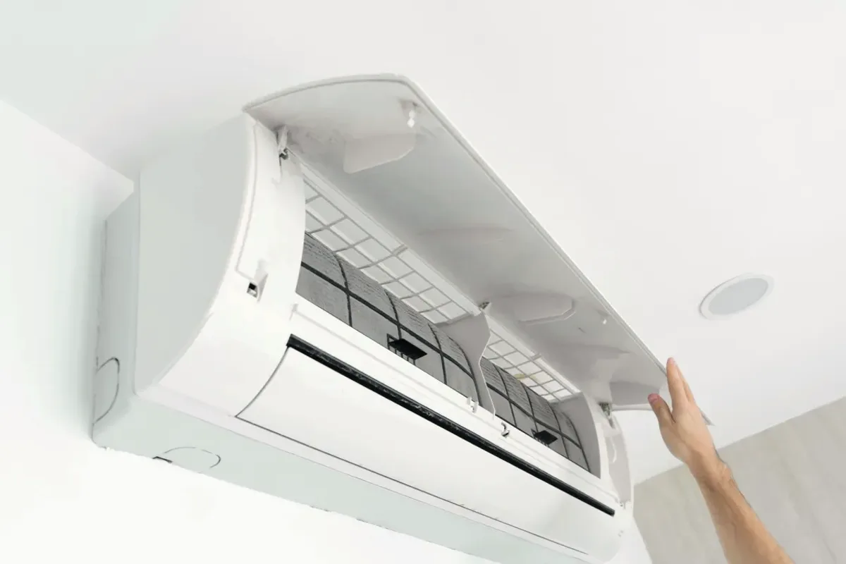 Hand opening the cover of a wall-mounted ductless air conditioner